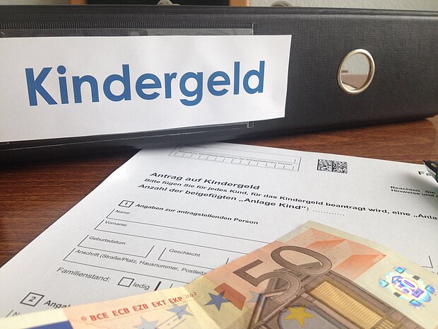 Ordner mit der Aufschrift "Kindergeld", einem Dokument davor und ein Euro-Geldschein