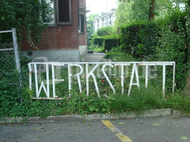 vor einem Haus ein Schild "Werkstatt"