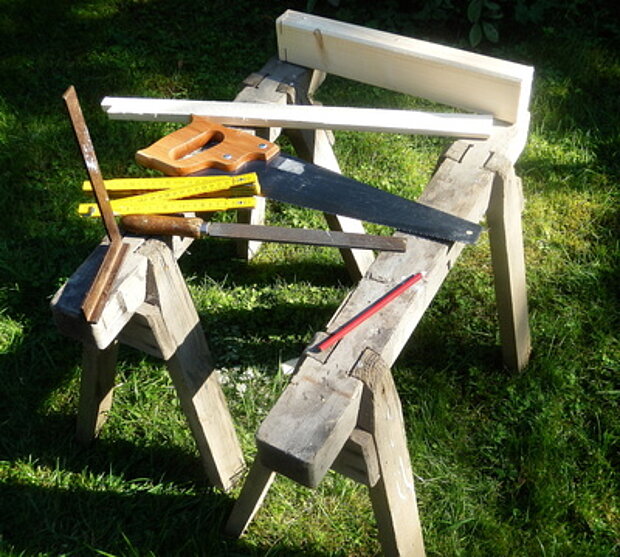 Werkzeuge wie Zollstock, Säge u.a. auf einem Holzbock