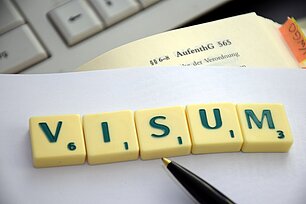 Buchstabensteine bilden das Wort "VISUM"