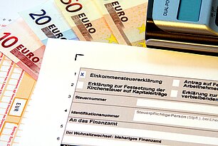 Formular für Steuererklärung, Taschenrechner und Geldscheine