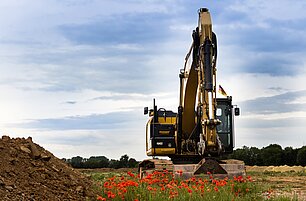 Bagger gräbt auf grüner Wiese