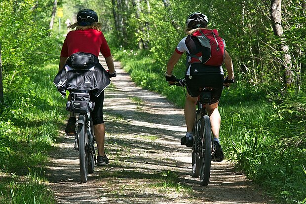 zwei Fahrradfahrer fahren einen Waldweg entlang