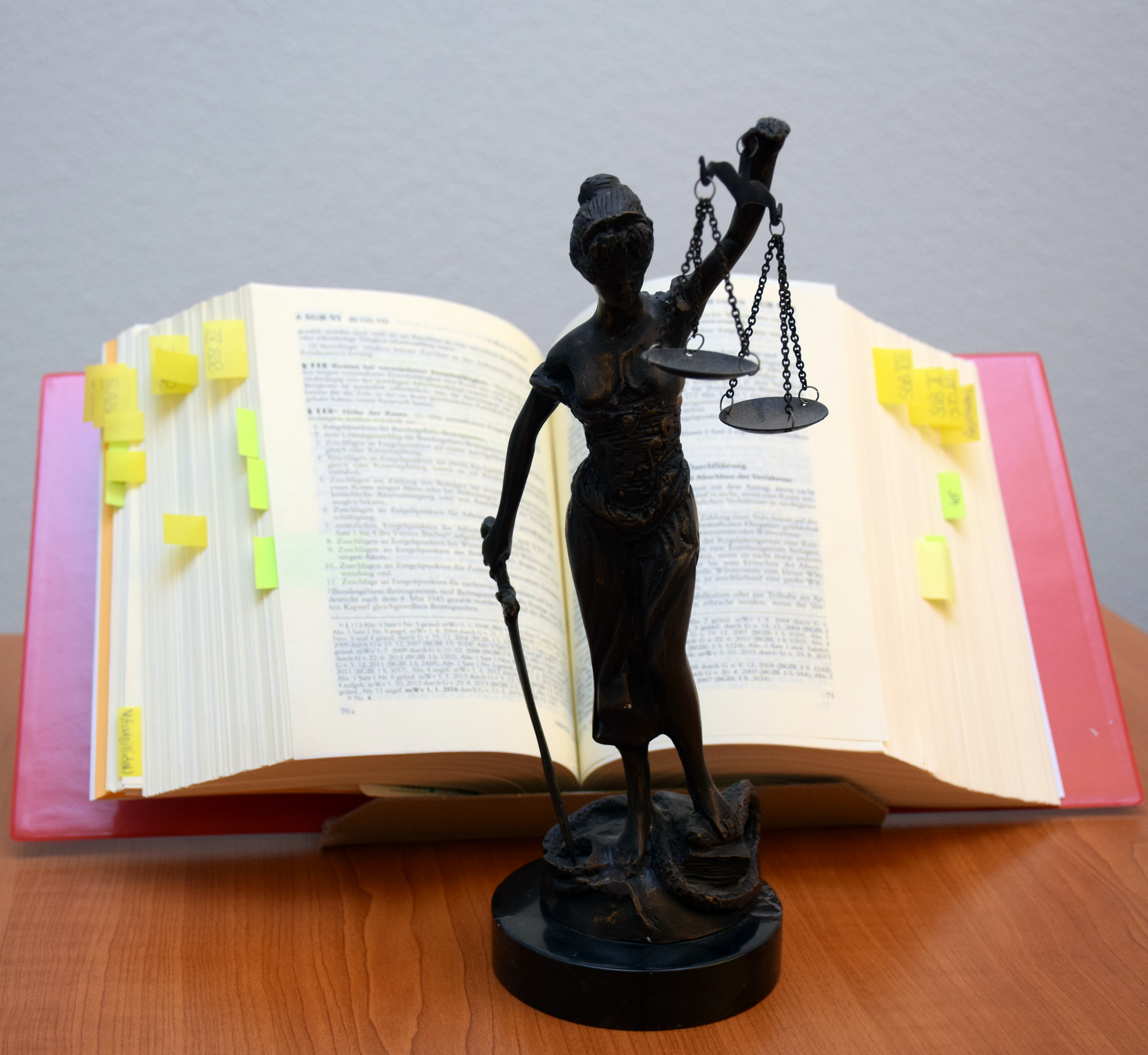 Statuette Justitia vor aufgeschlagenem Gesetzbuch