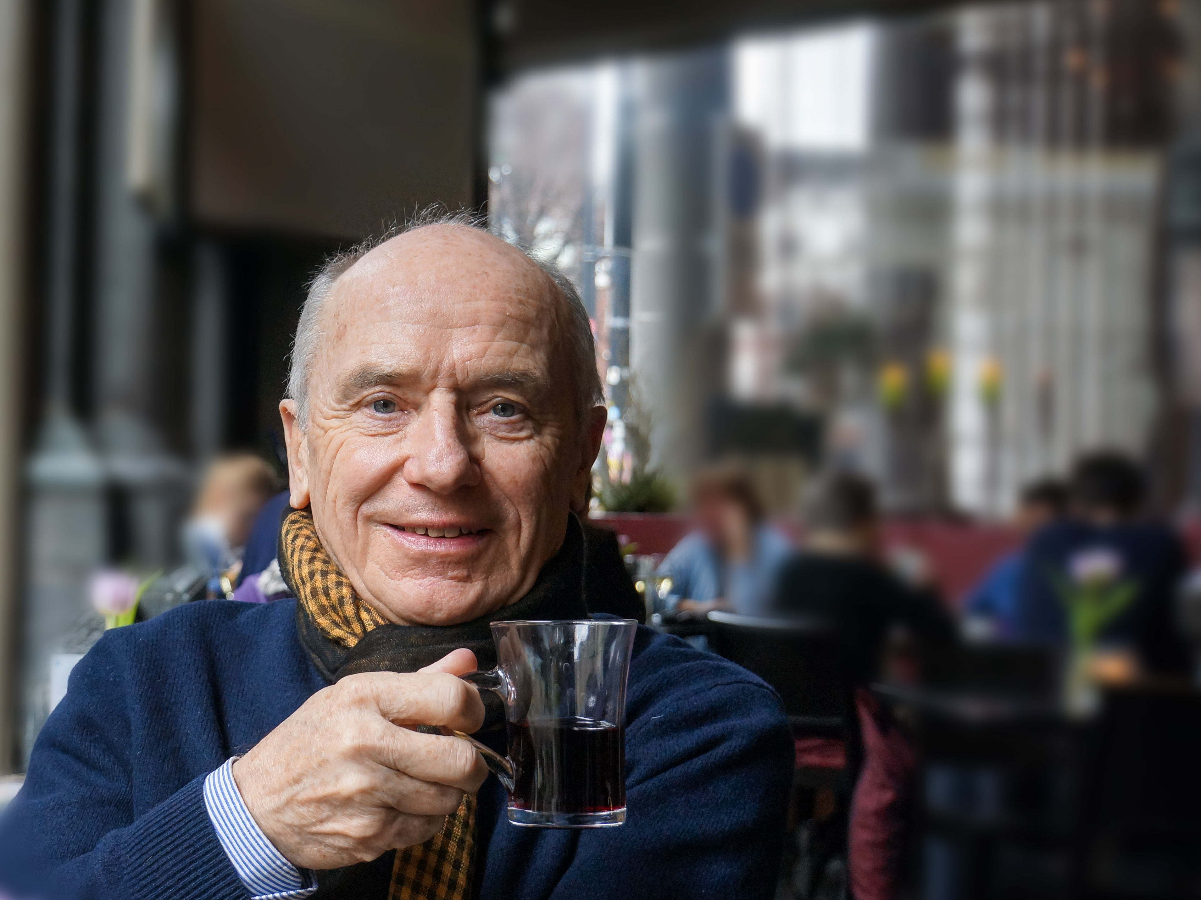 Rentner mit Kaffeetasse in der Hand schaut in die Kamera